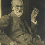 Retrato em preto e branco de Sigmund Freud sentado e segurando um charuto